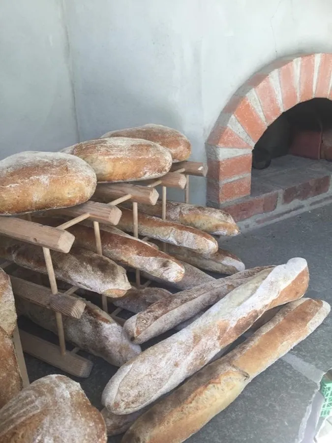 Nybakte brød og baguetter på trestativ foran den vedfyrte mursteinsovnen – starten på Landøy
