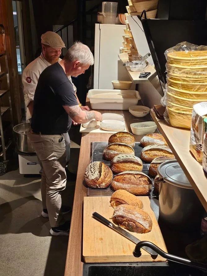 Bakere med ferske surdeigsbrød på rist under surdeigskurs hos Landøy Brød & Pizza i Mandal